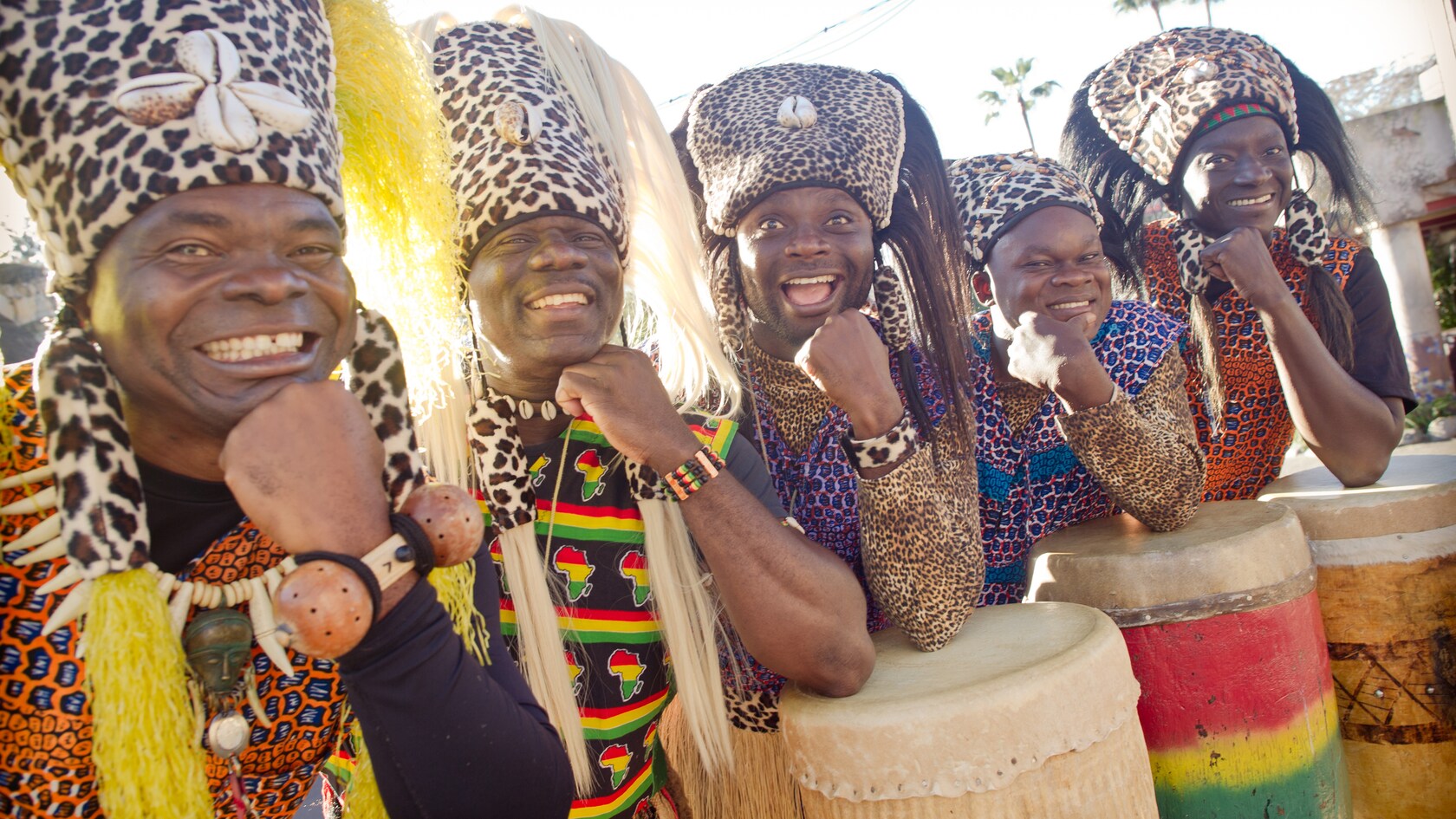 Los 5 miembros de Tam Tam Drummers of Harambe posan con el codo apoyado sobre los tambores de conga