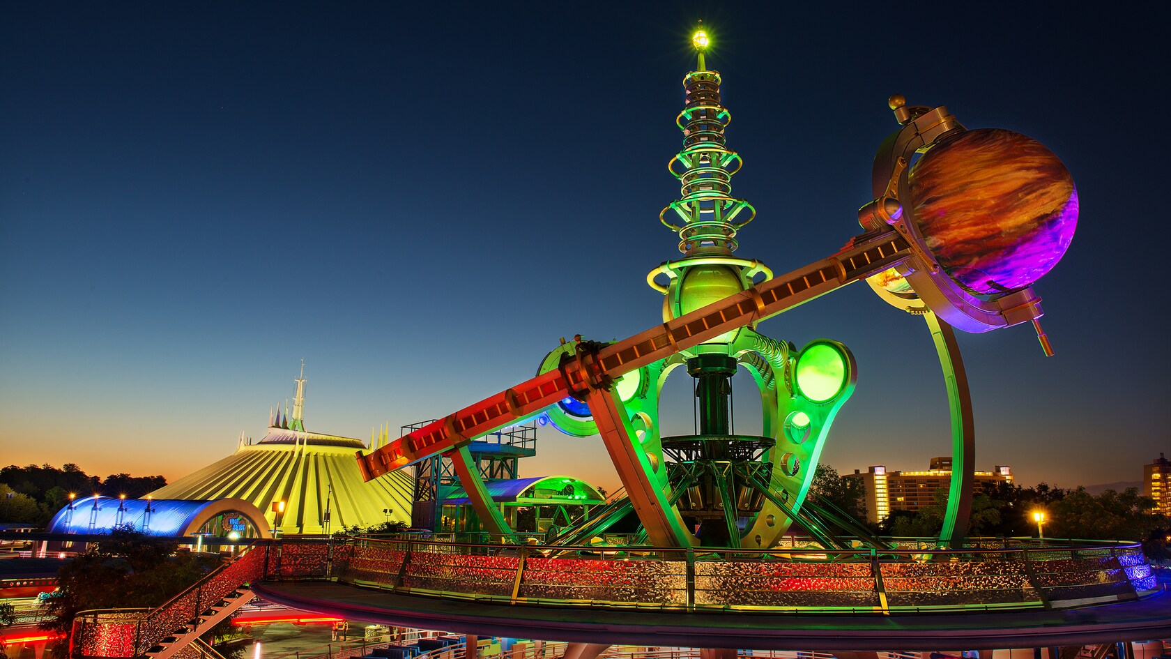 La futurística y colorida atracción Astro Orbiter iluminada de noche en Tomorrowland