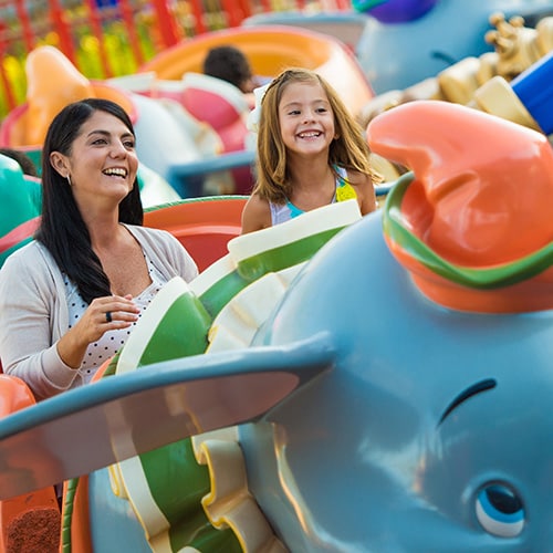 A mother and daughter gleefully ride in a Dumbo-looking car on Dumbo the Flying Elephant