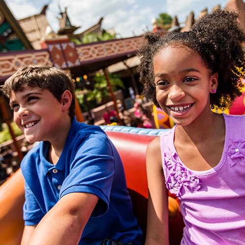 A boy and girl ride The Magic Carpets of Aladdin attraction at Magic Kingdom park