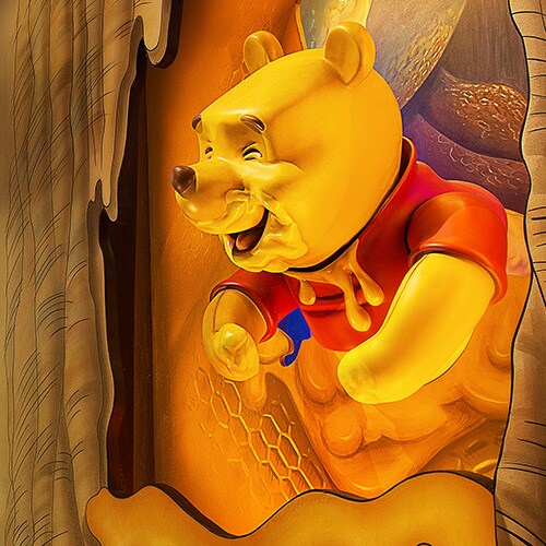 Winnie the Pooh covered in honey peeking out of a tree at The Many Adventures of Winnie the Pooh