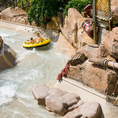 Two people ride an oversized inner tube on Gangplank Falls waterslide at Disney's Typhoon Lagoon water park