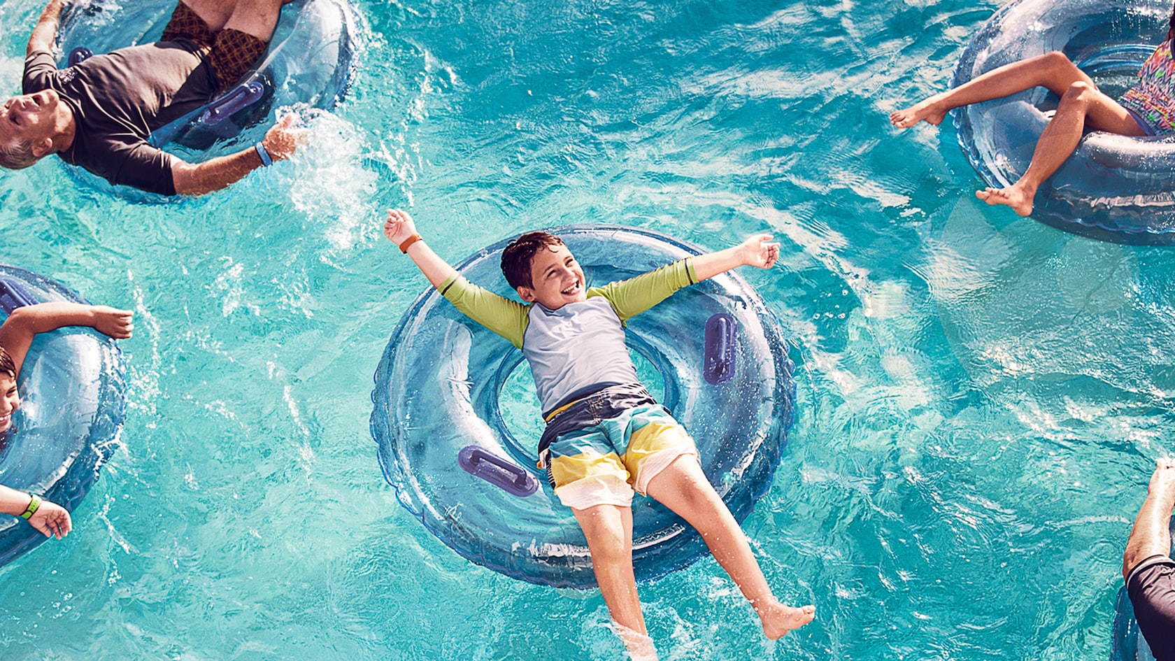 A group of kids lounge on their individual inner tubes and float in a swimming pool