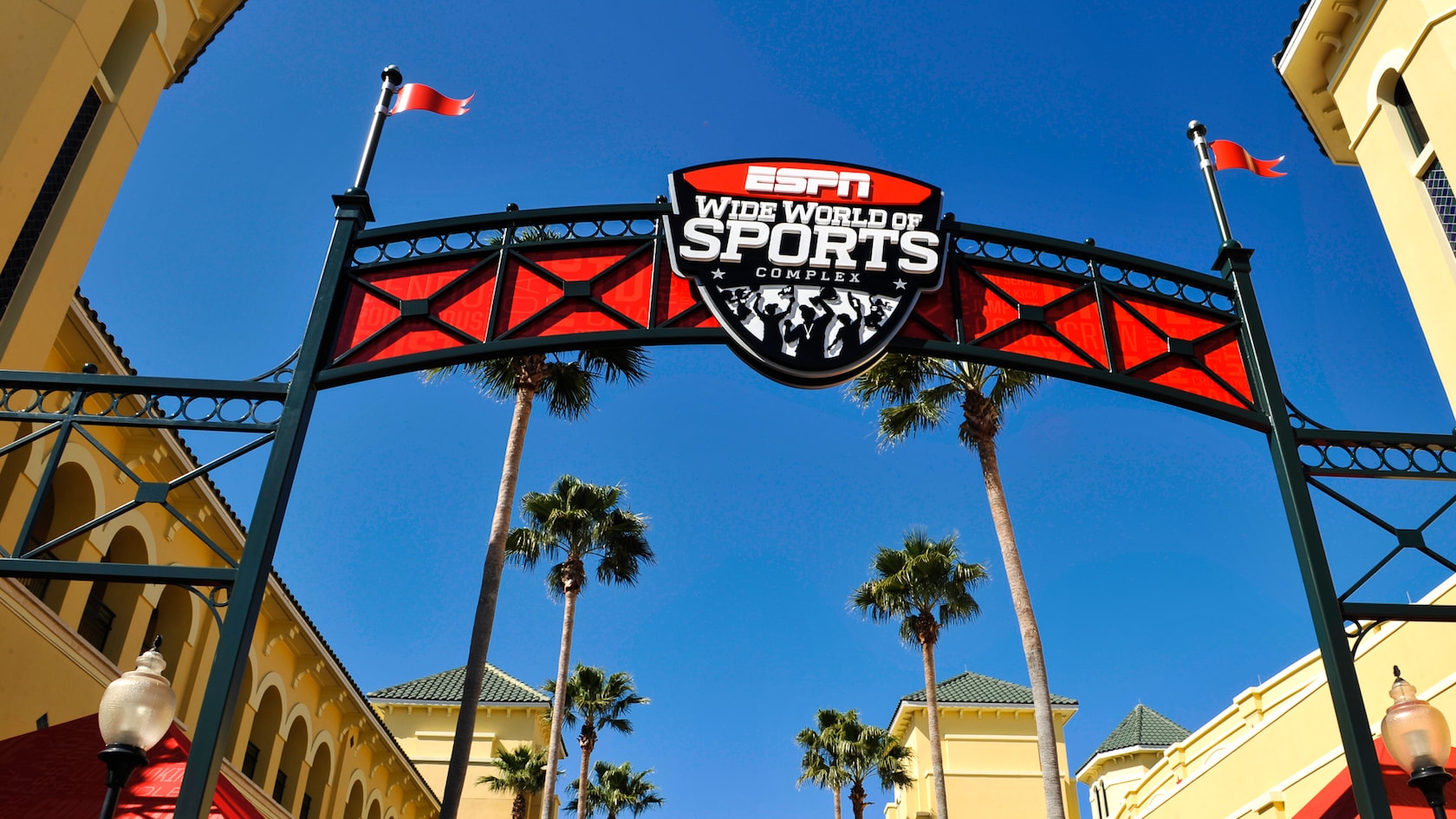 A red banner sign forms an archway above an entrance that reads: “ESPN Wide World of Sports Complex”