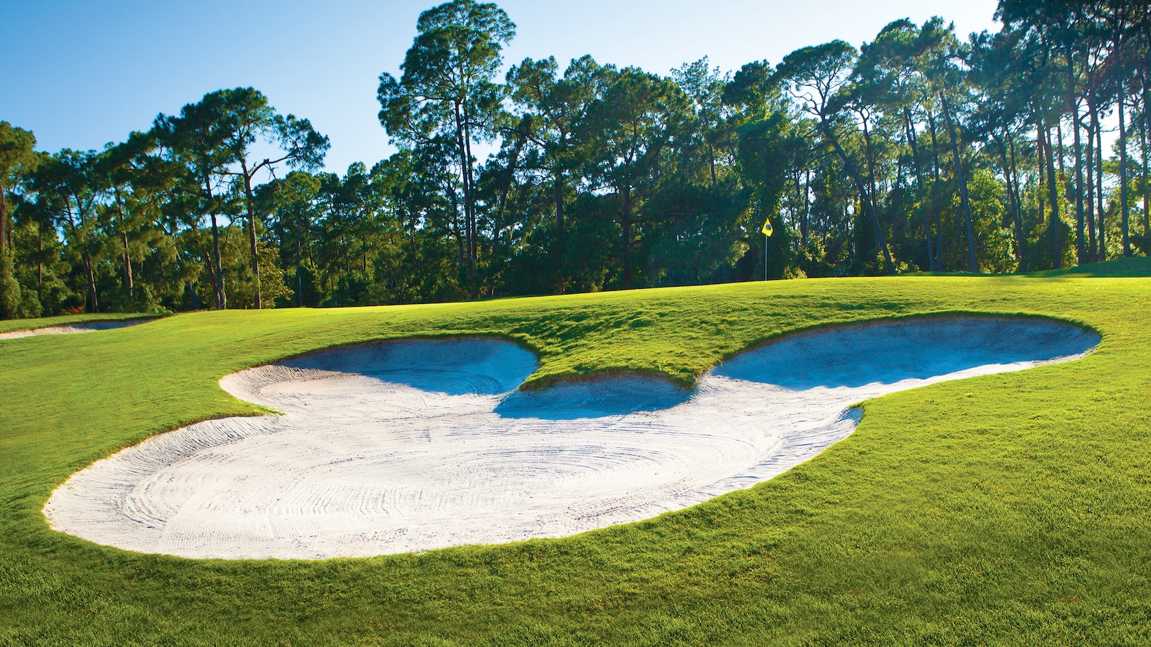 Um banco de areia no formato do ícone do Mickey perto de um buraco no Disney's Magnolia Golf Course