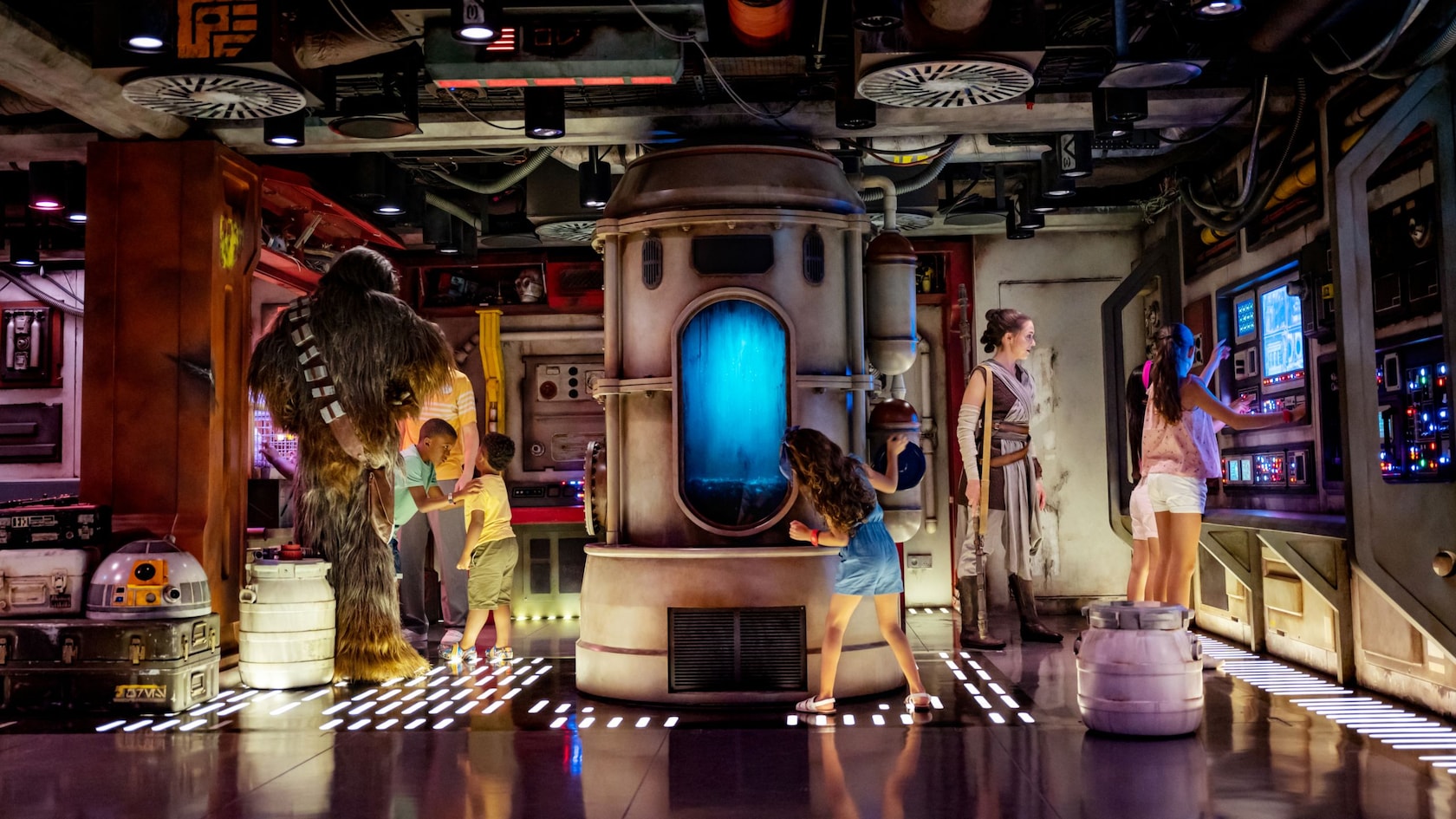 Rey and Chewbacca watch on as children explore the cargo area of a Star Wars ship