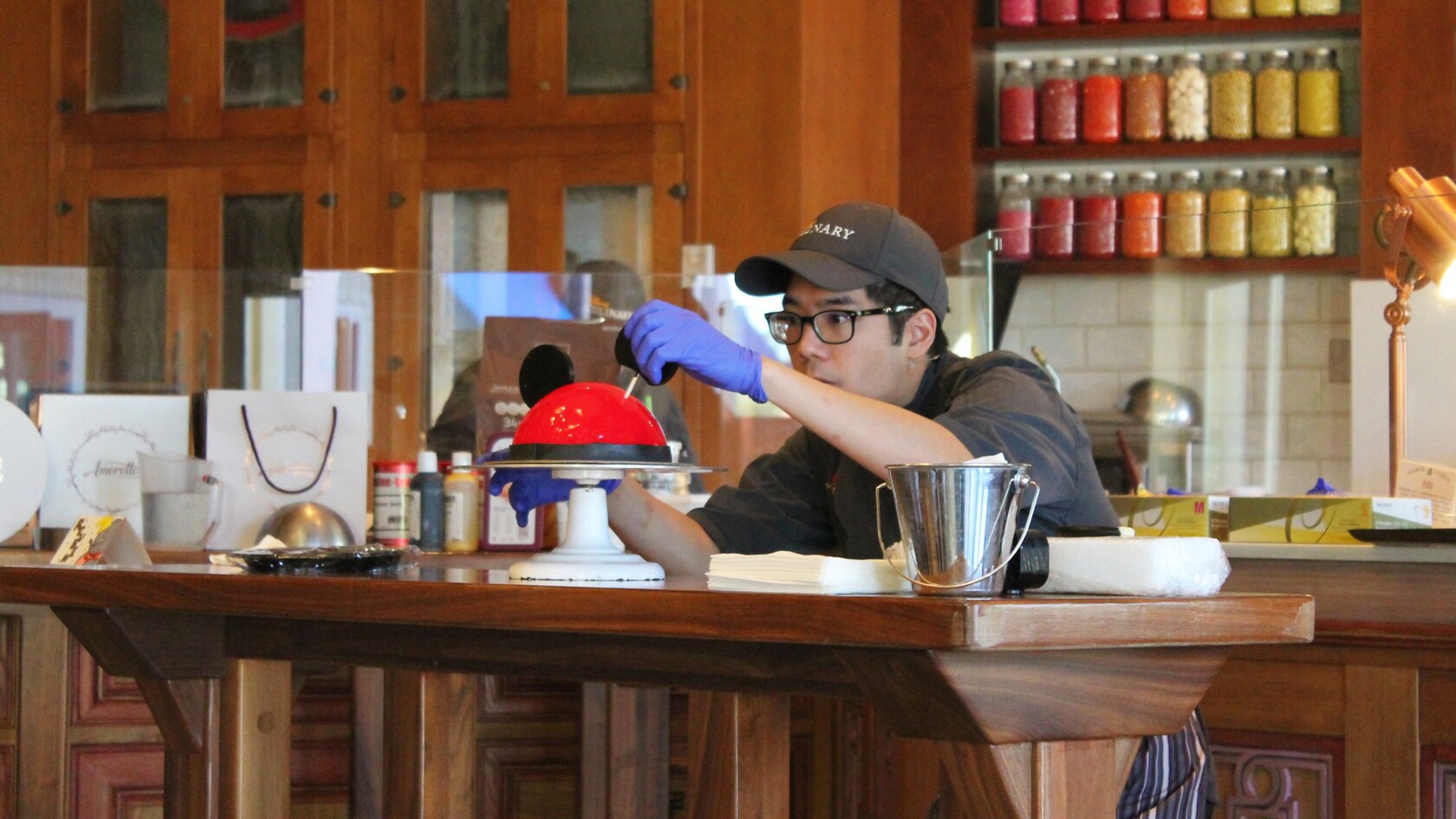 A pastry artist decorating a Petite Mickey Mouse Dome cake at Amorette’s Patisserie