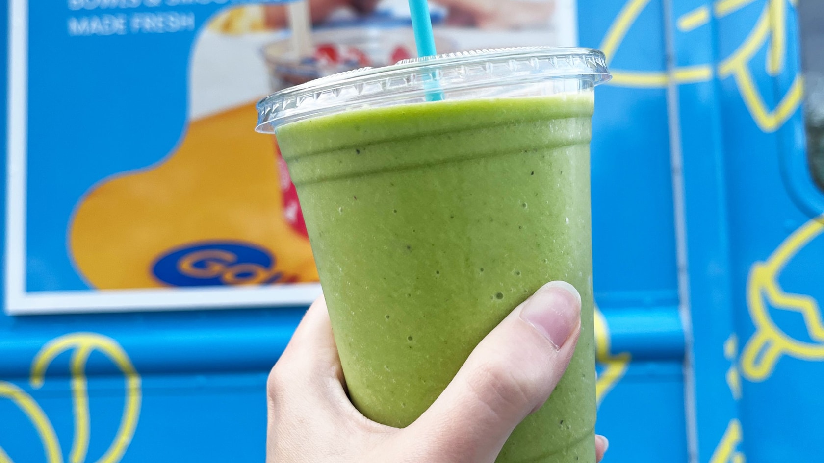 A smoothie in a plastic cup near a food truck