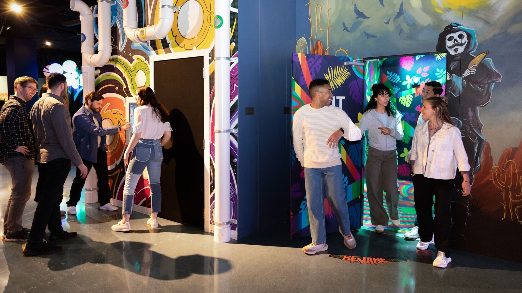 Two groups of people entering separate challenge rooms with murals and a Beware floor graphic