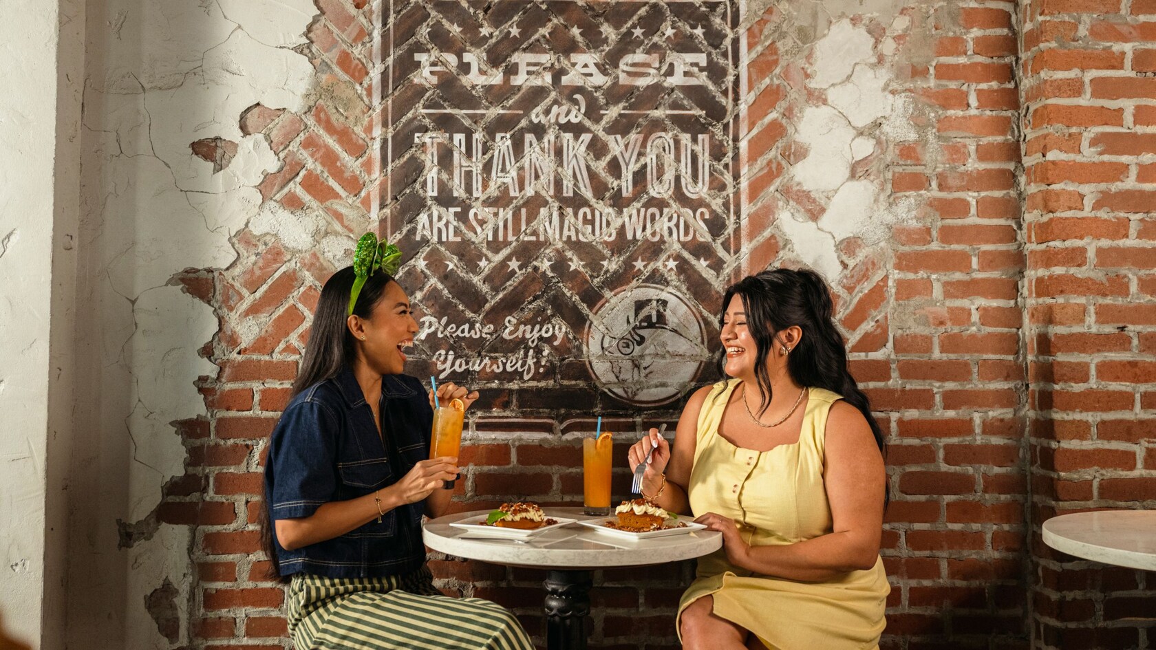 Two women enjoying drinks and a meal at a small table at The Polite Pig in Disney Springs