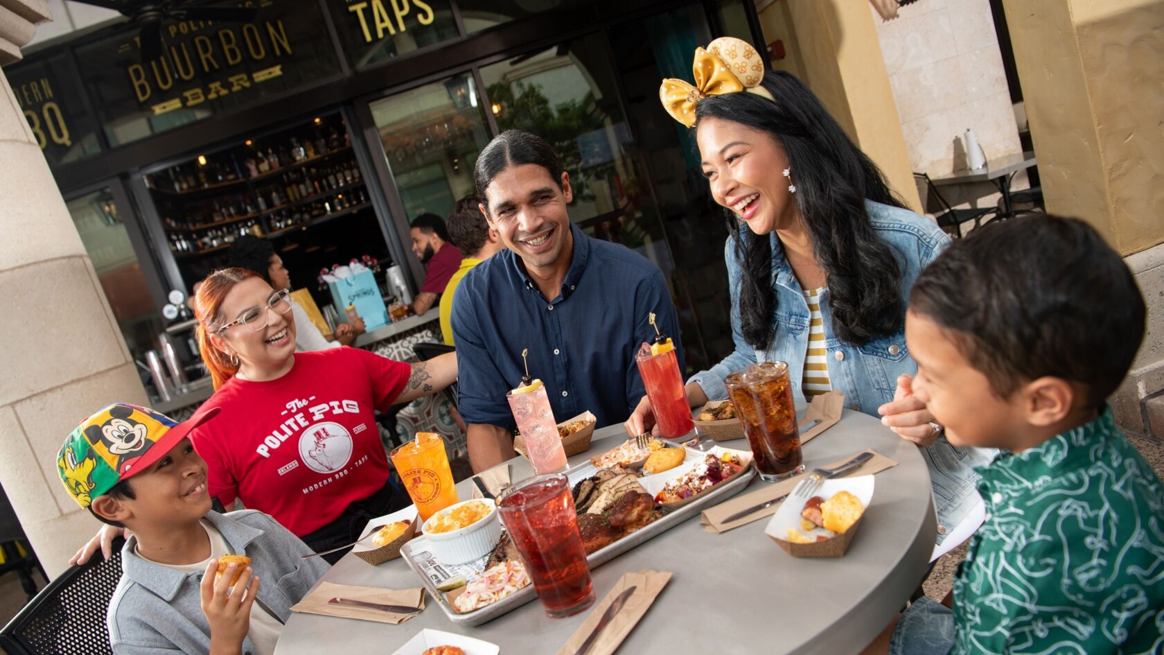 A smiling group enjoying barbecue and beverages at The Polite Pig in Disney Springs