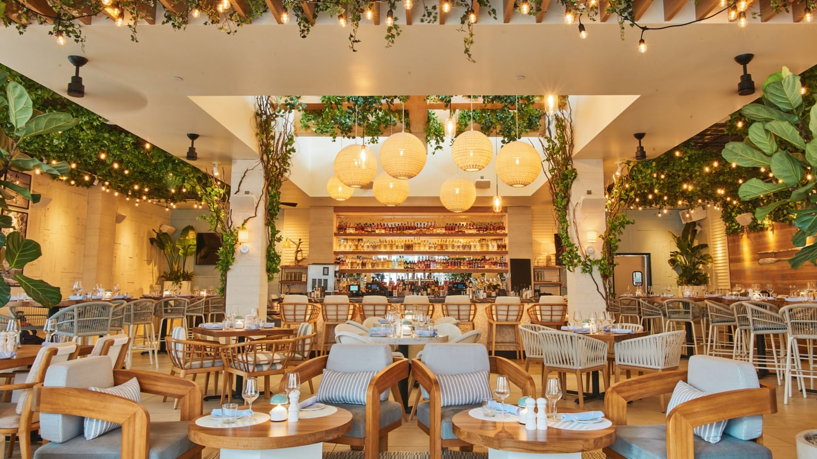 Un restaurante con muchos asientos y un bar grande decorado con faroles y plantas
