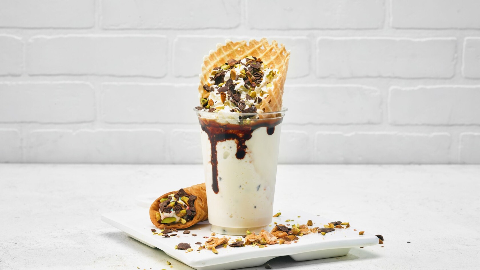 A Cannoli Shake featuring whipped cream, pistachios, chocolate pieces and a waffle cone