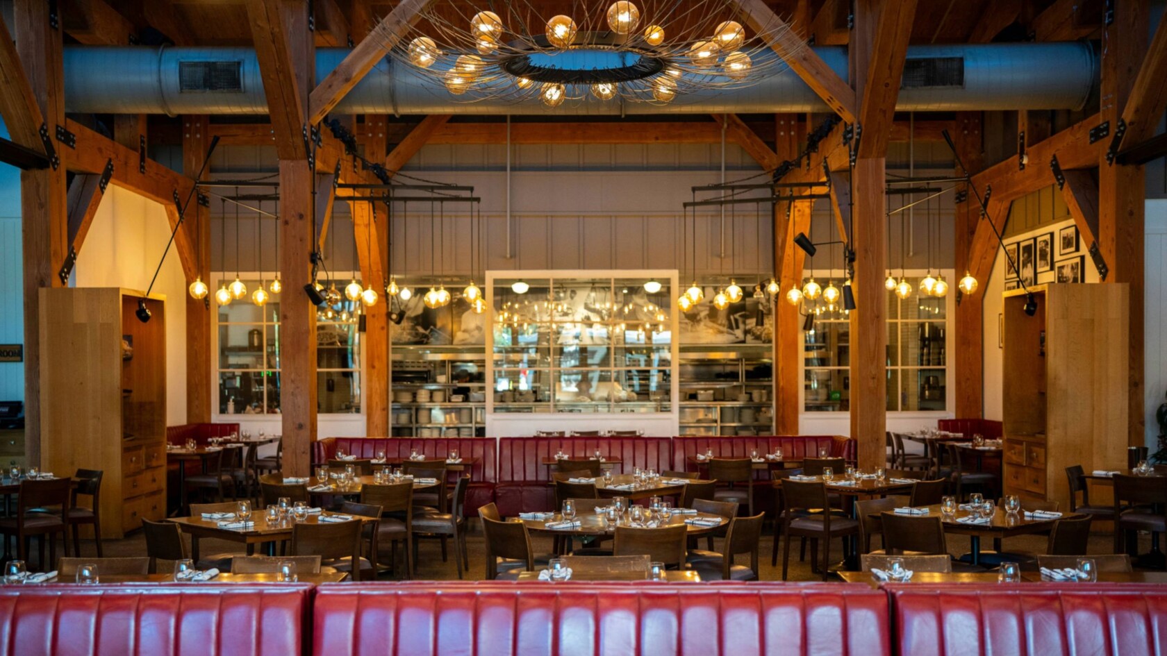 A restaurant with a large light fixture hanging over many round tables
