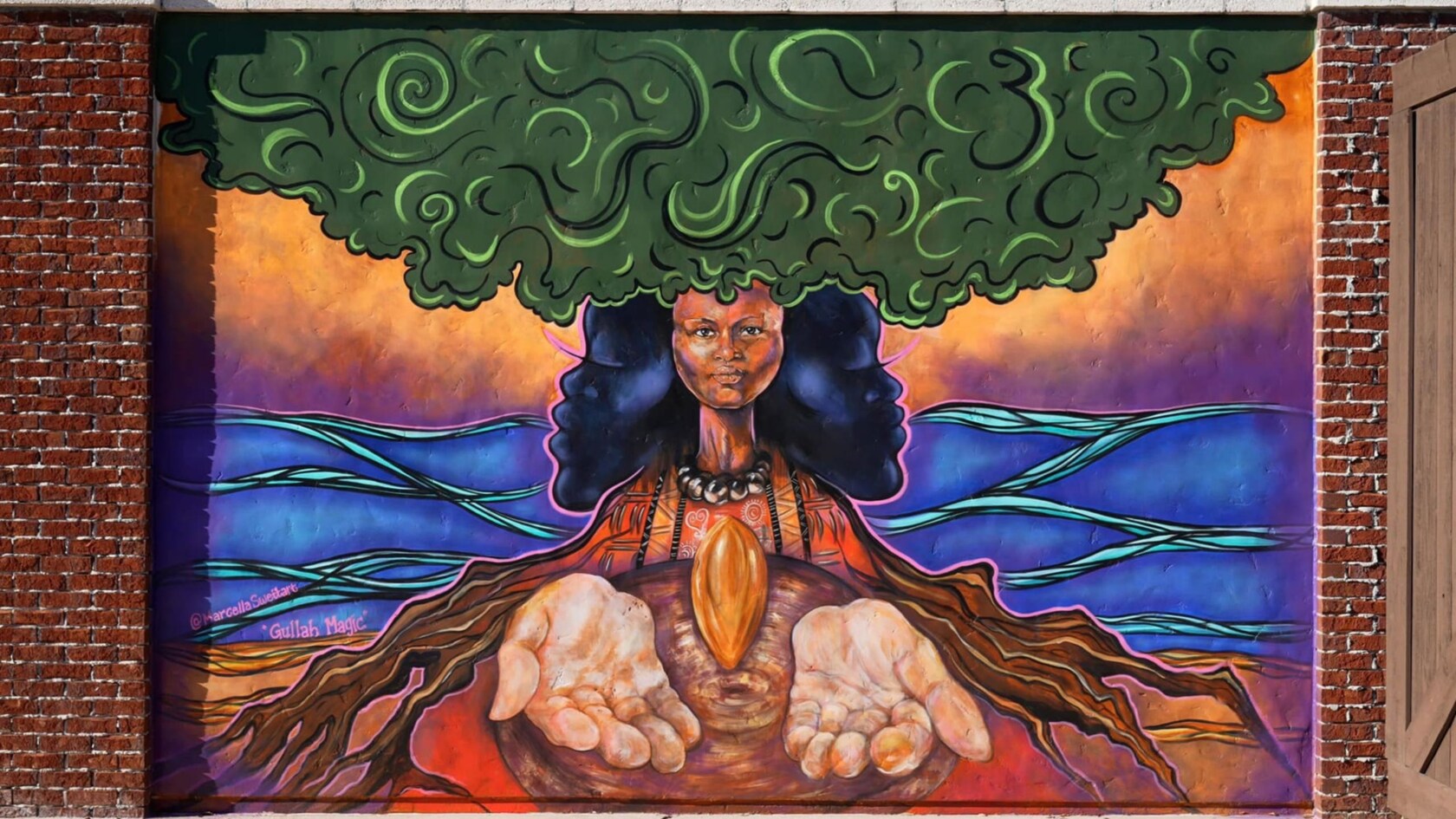 Un mural de una mujer con cabello similar a un árbol con las manos abiertas sosteniendo una semilla