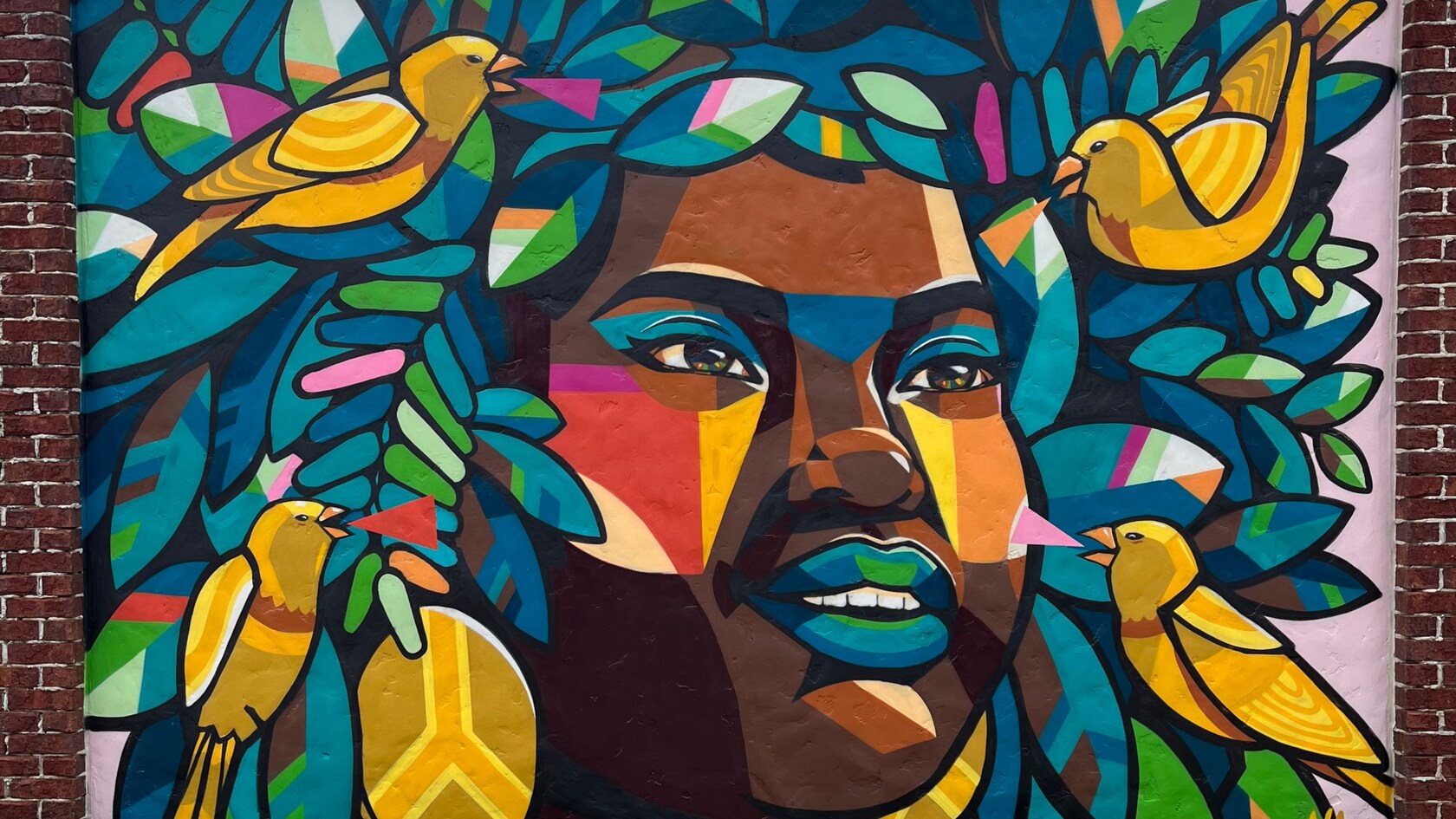 Un mural de la cara de una mujer rodeada de cuatro aves