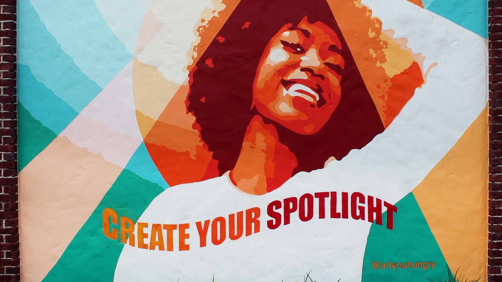 Un mural de una mujer sonriente y las palabras ‘Create Your Spotlight’