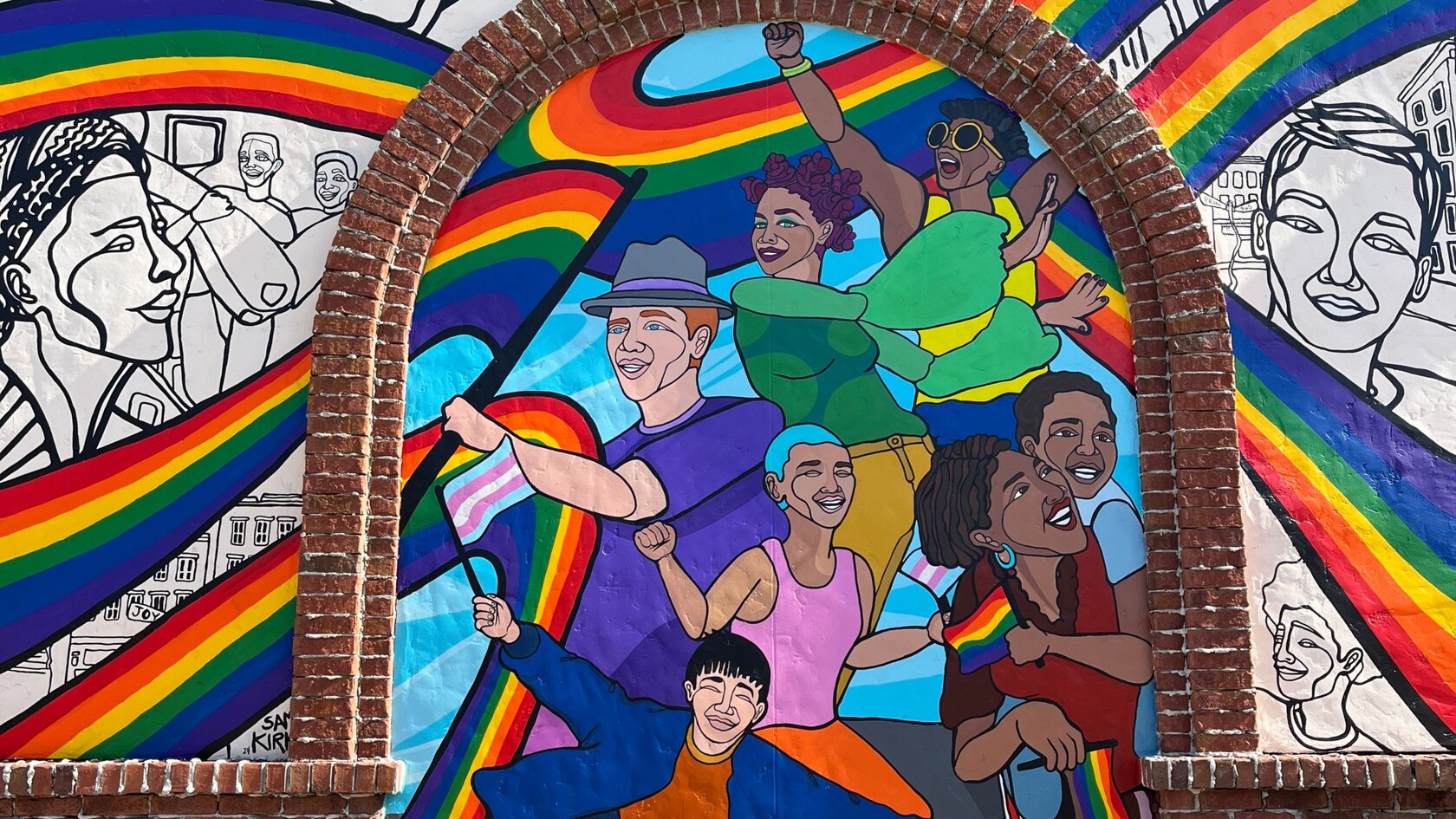 Un mural de la artista Sam Kirk que presenta a diversas personas bailando bajo un arcoíris enmarcados por arcos de ladrillo y bocetos de rostros