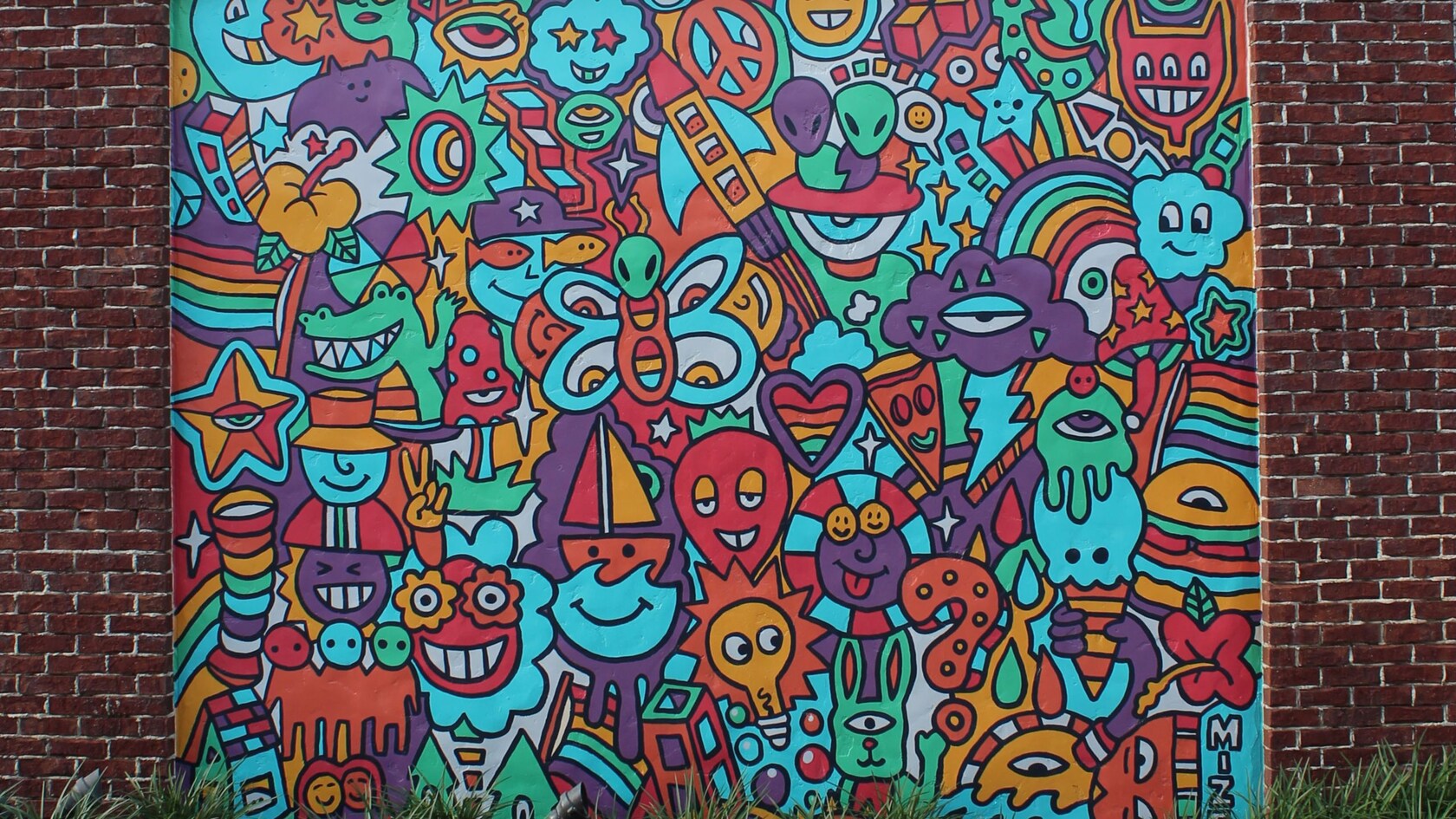 Un mural de cohetes, arcoíris y otras formas en una pared de ladrillo