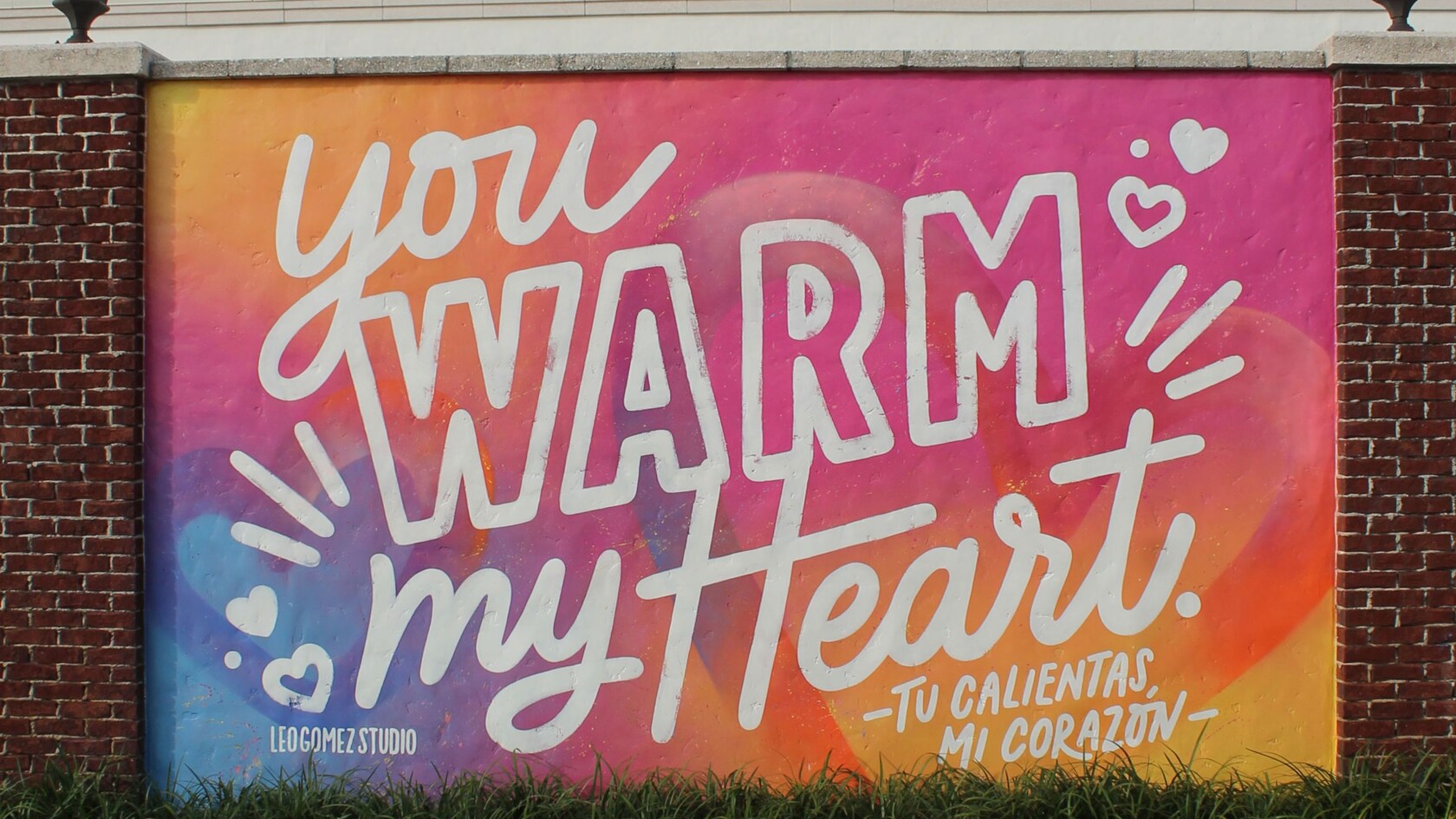 Un mural en una pared de ladrillo con las palabras ‘You Warm My Heart’