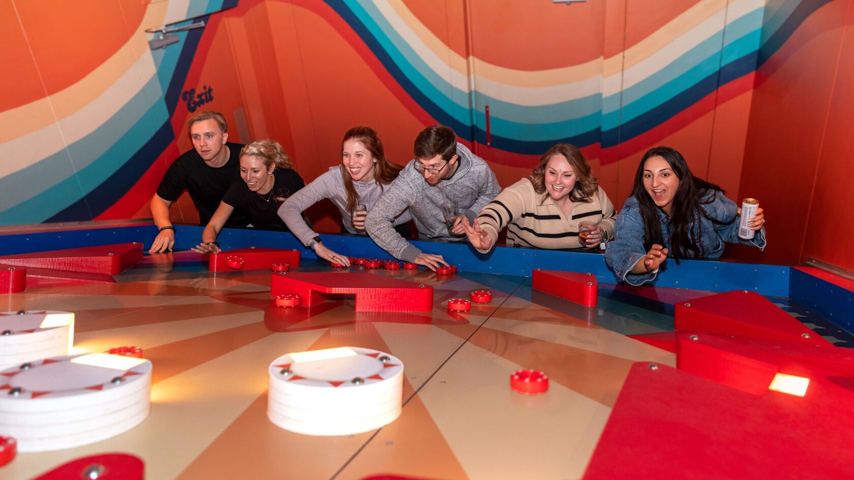 A group of Guests playing pinball on a giant table using pucks thrown by hand