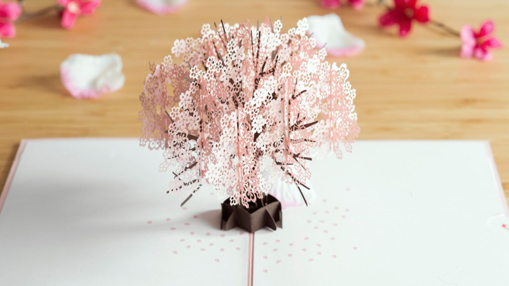 A Lovepop Cherry Blossom Pop Up Card featuring paper that’s been cut and arranged to look like flower blooms on a tree