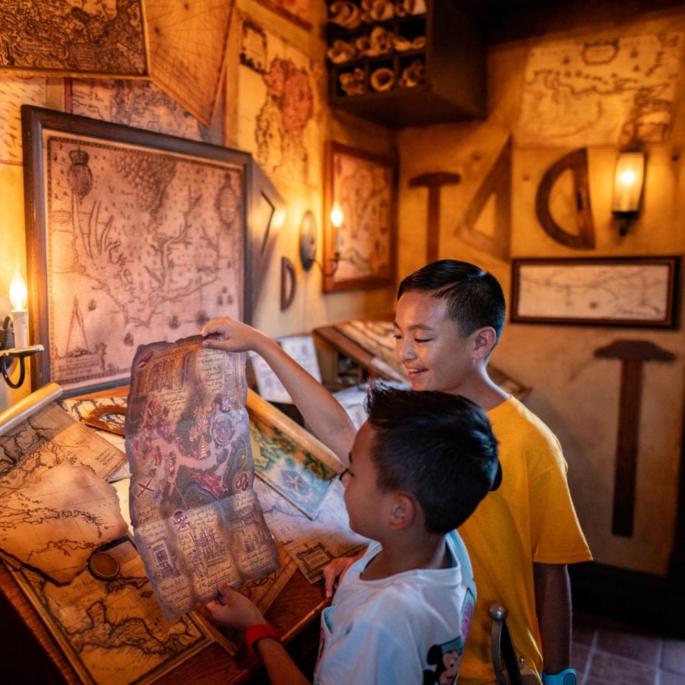 Two young Guests reading a treasure map in The Crow’s Nest at Magic Kingdom park