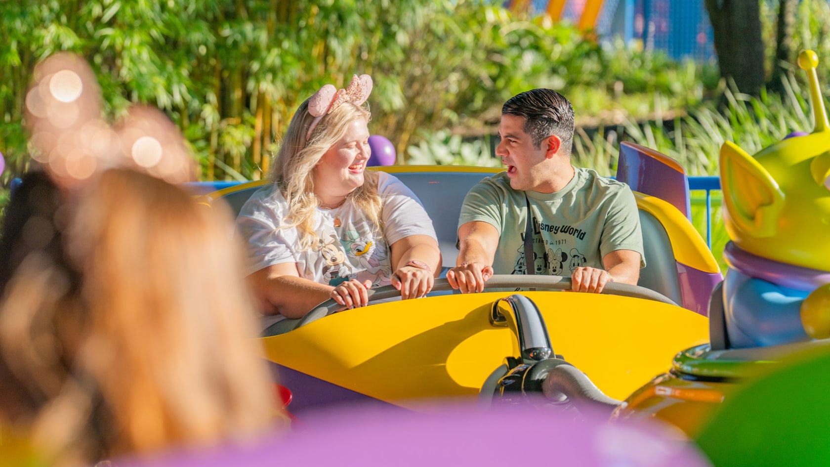 Dos Visitantes se miran mientras disfrutan la atracción Alien Swirling Saucers en Toy Story Land