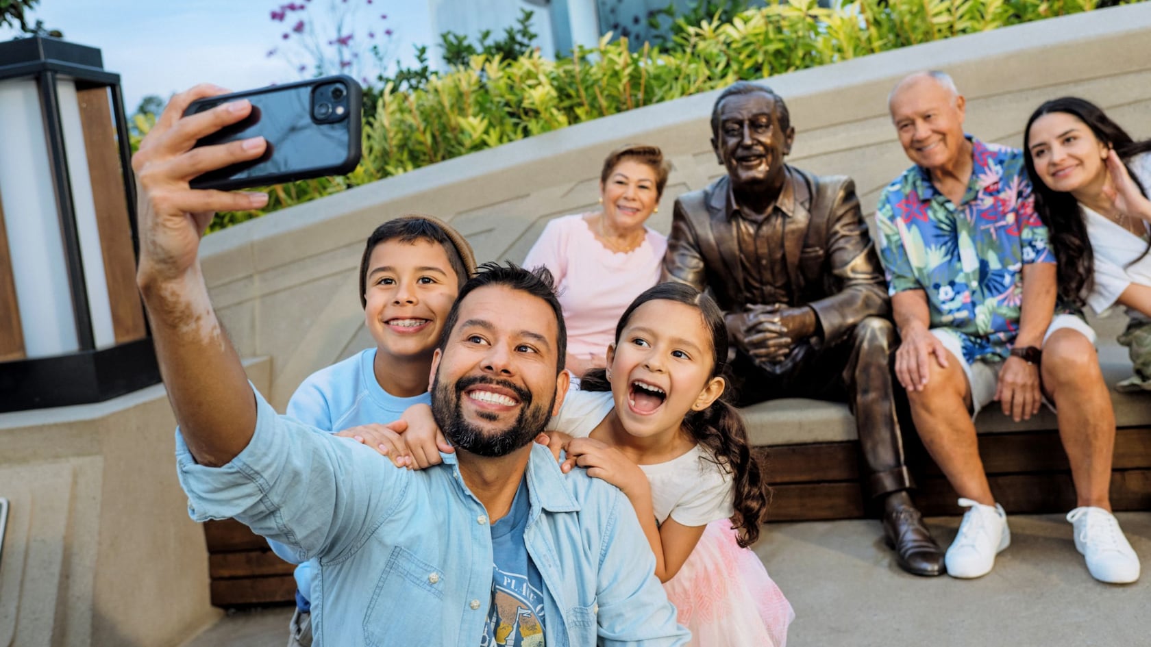 A group of people taking a selfie with the ‘Walt the Dreamer’ statue in World Celebration Gardens