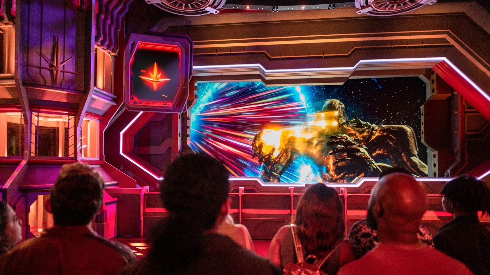 Guests watching a cosmic battle scene on screen in the Guardians of the Galaxy Cosmic Rewind queue