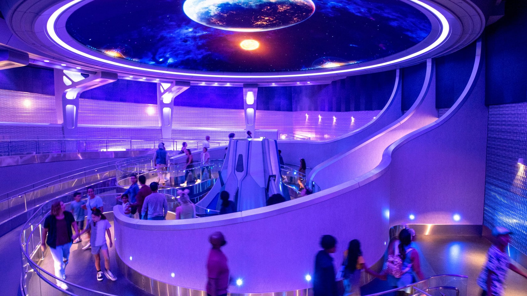 Guests walking through the queue at Guardians of the Galaxy: Cosmic Rewind beneath a glowing cosmic ceiling display