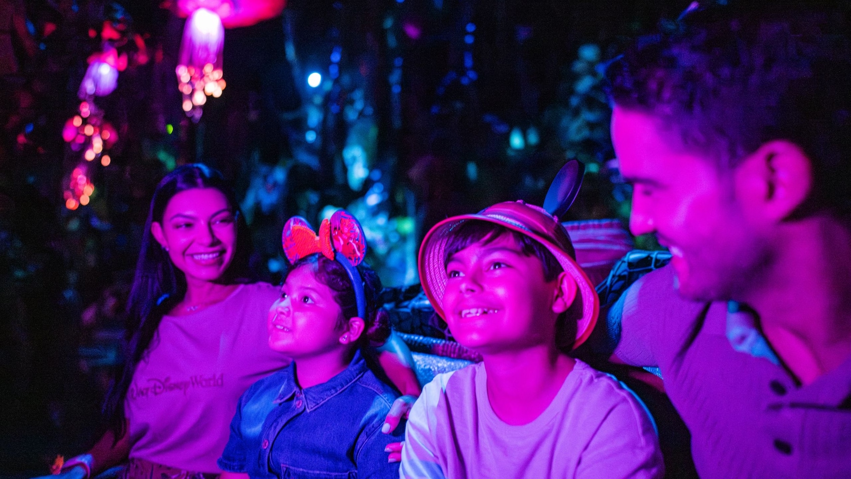 Una familia de 4 integrantes sonriendo mientras viaja por la atracción Navi River Journey en Disney’s Animal Kingdom Theme Park