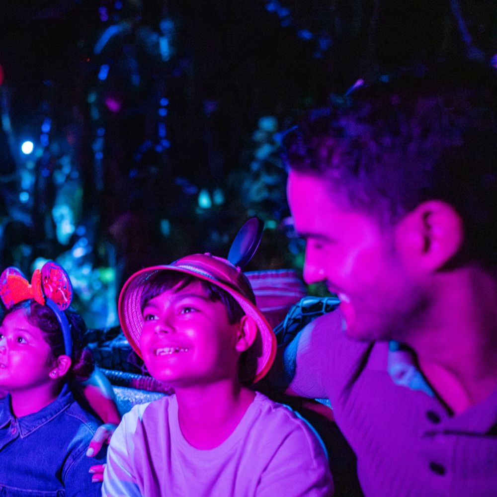 A family of 4 smiling while traveling through the Navi River Journey attraction in Disney’s Animal Kingdom theme park