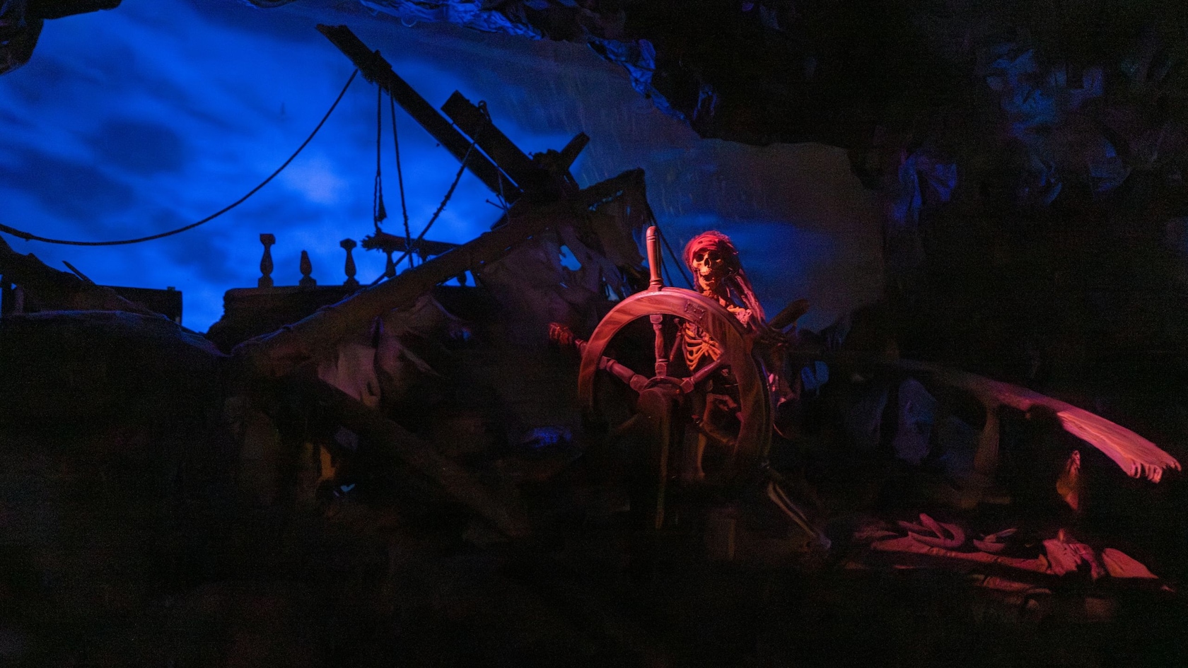 A scene from the Pirates of the Caribbean attraction featuring a pirate helming a ship