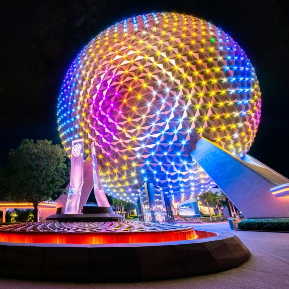 The prism pylon fountain in front of an illuminated Spaceship Earth at Epcot