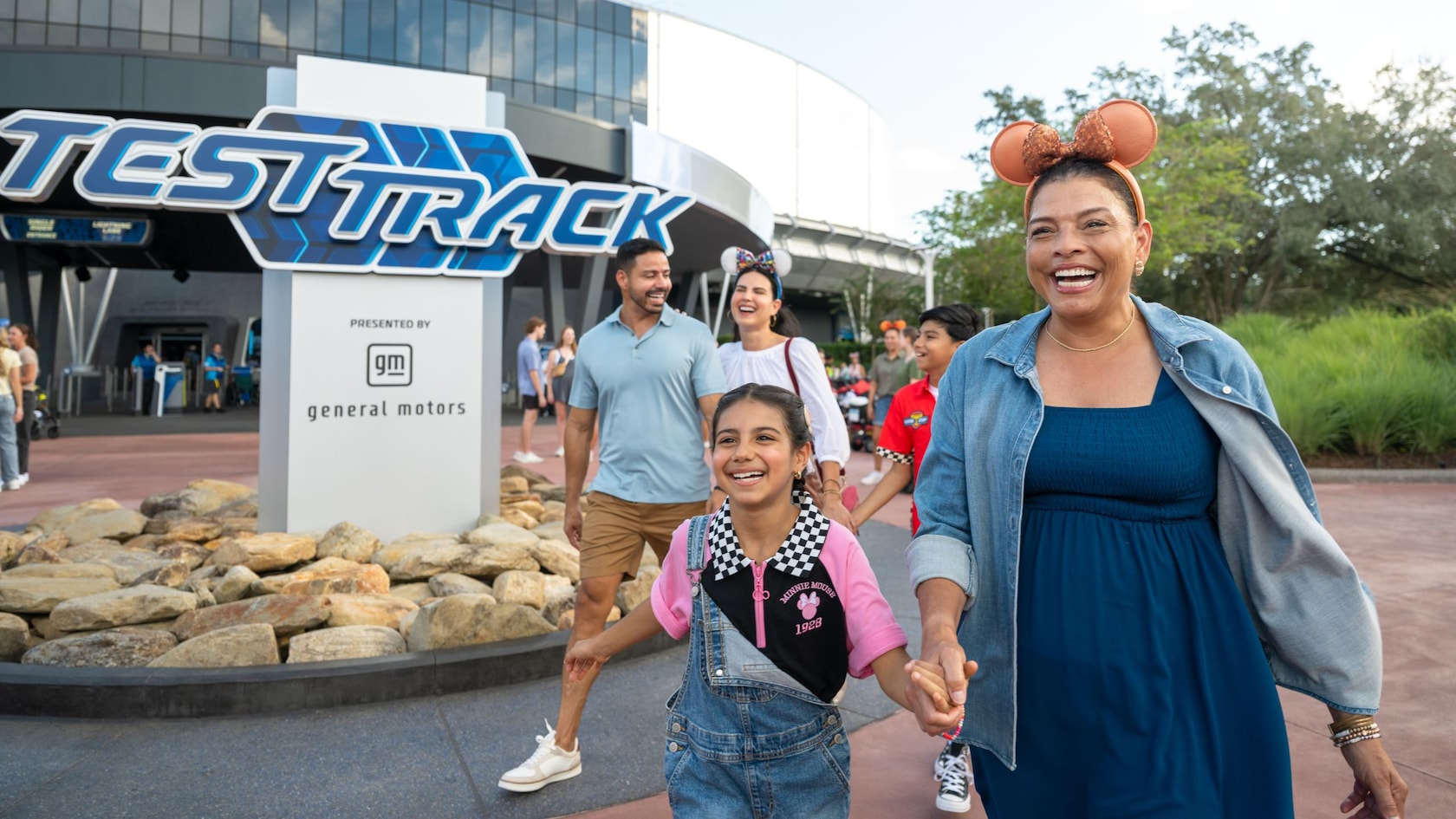 A family of 5 Guests smiling as they walk out of Test Track at Epcot