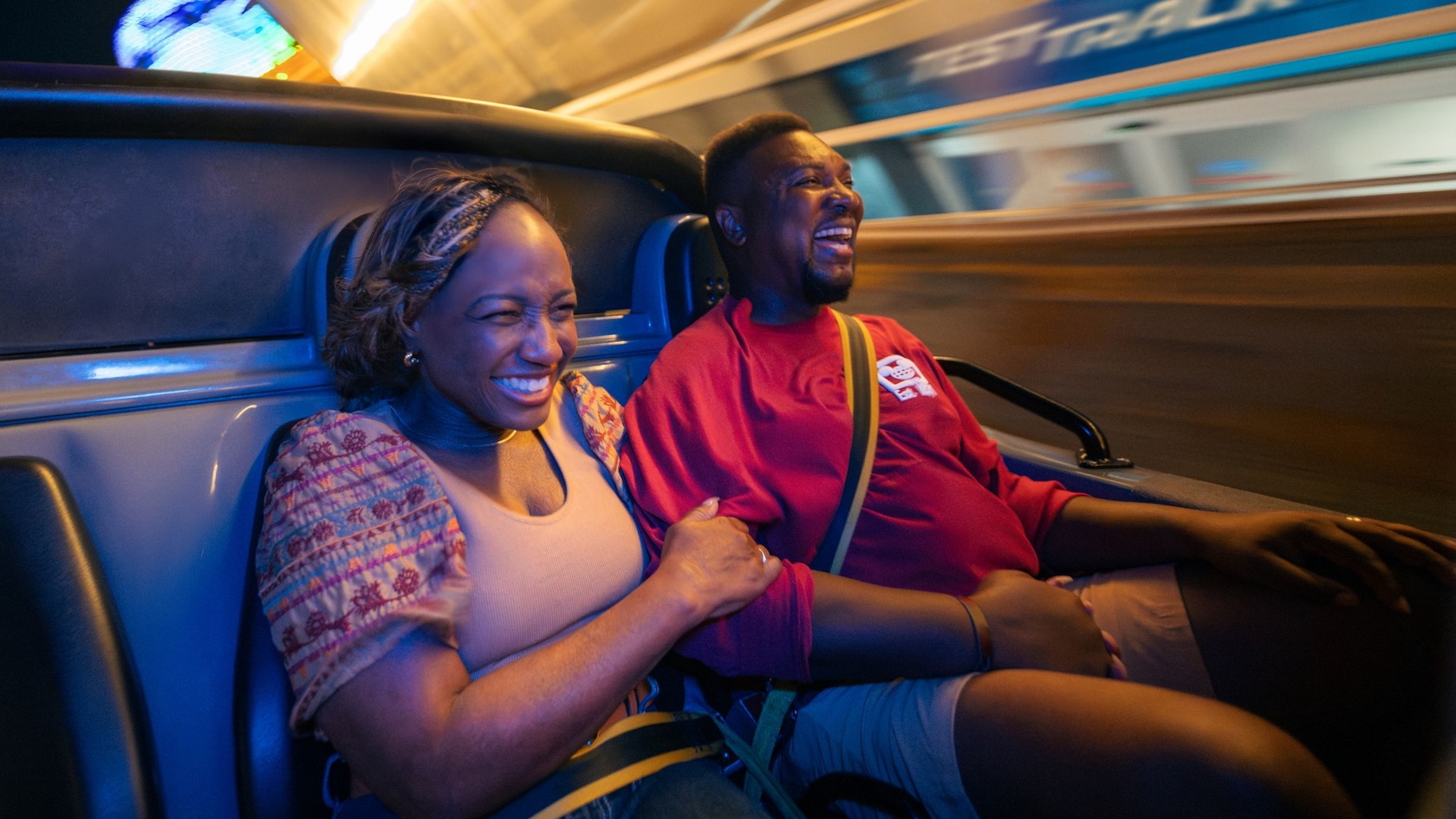 A couple smiling as they ride in a fast moving car in Test Track at Epcot