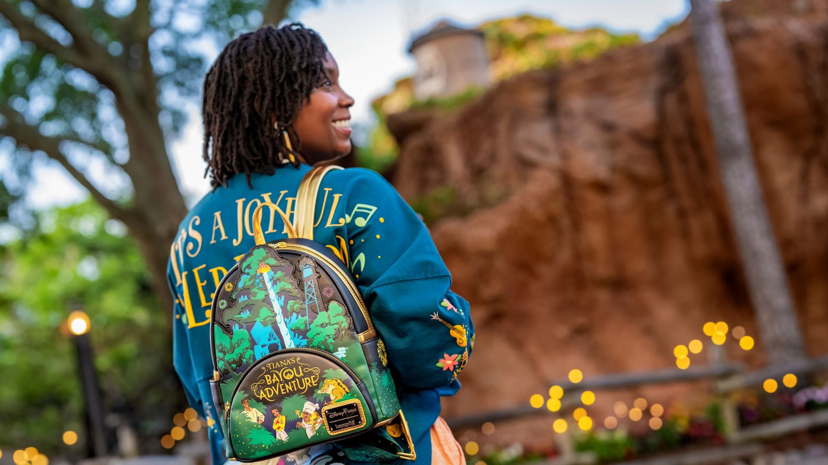 A woman with her back turned, wearing a Tiana’s Bayou Adventure Loungefly Mini Backpack and a jersey