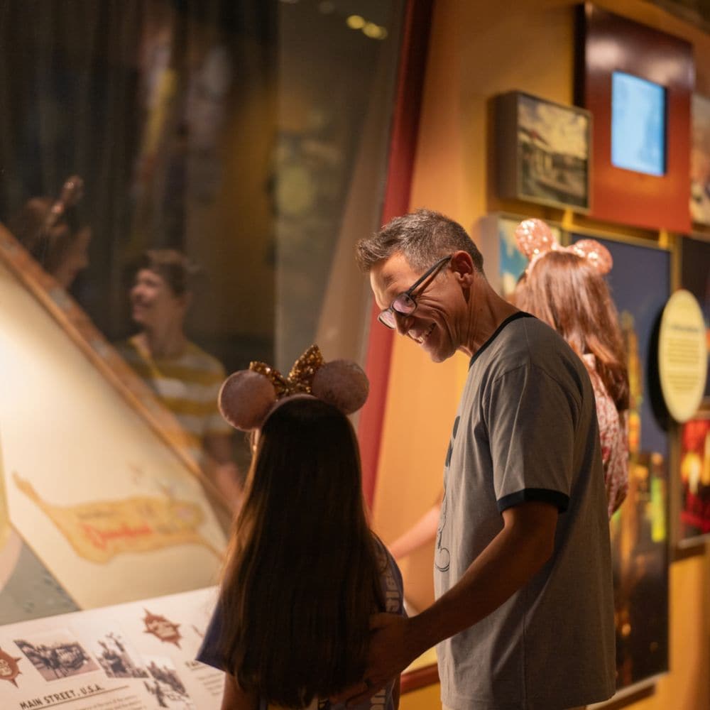 A father and daughter looking at a Walt Disney World Resort map in the Walt Disney Presents gallery at Disney’s Hollywood Studios