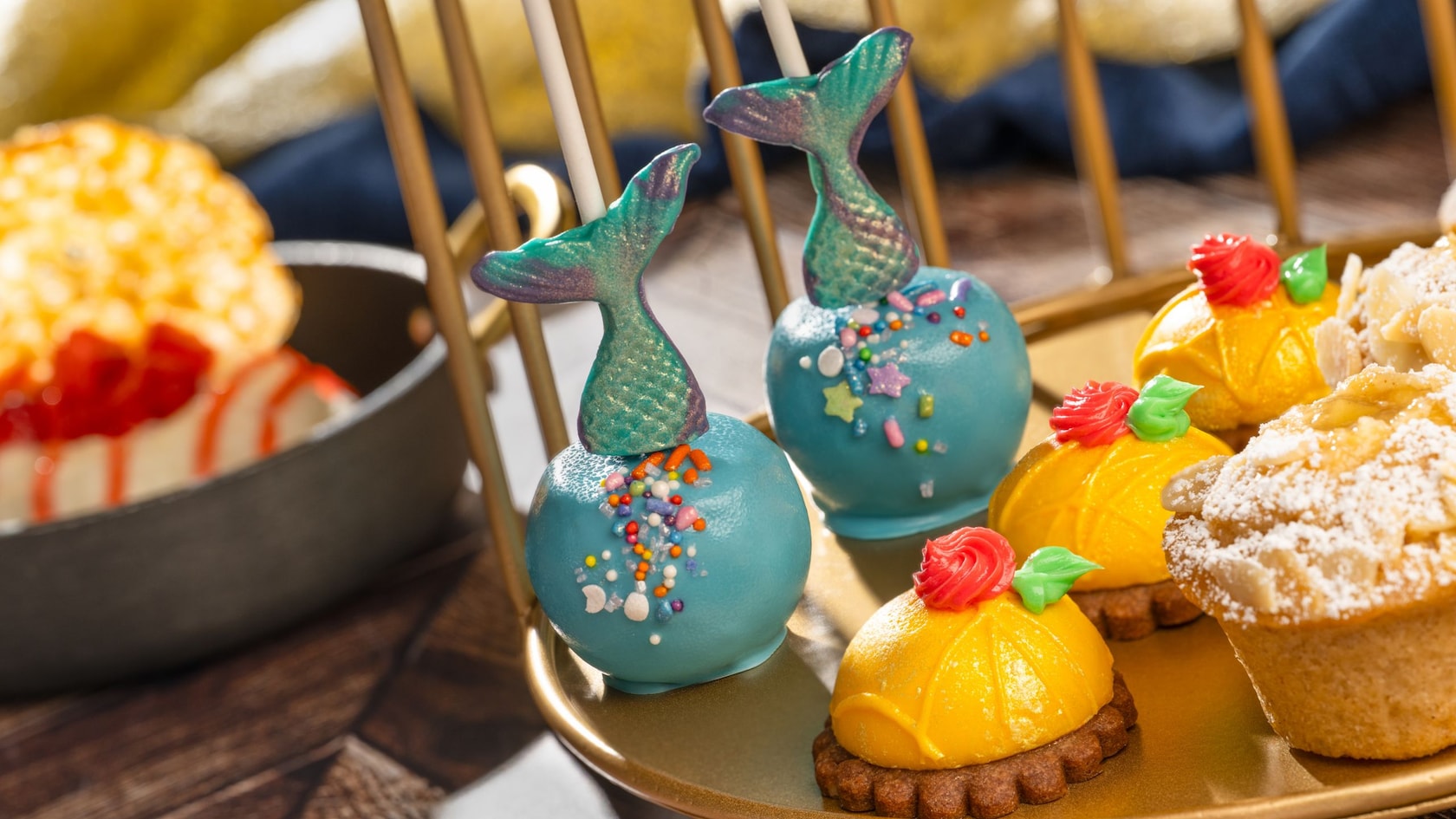 The Royal Chef’s Dessert Plate at Akershus Royal Banquet Hall, featuring an Ariel Cake Pop with a mermaid tail and a Belle Mousse Dome