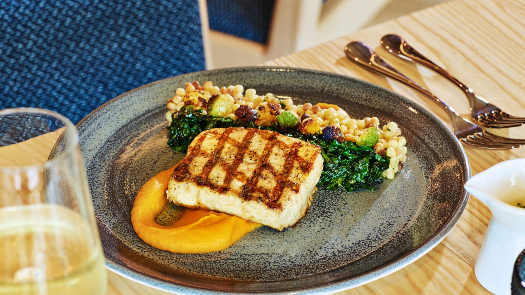 An appetizing plate of grilled mahi mahi and a side of kale with fregola