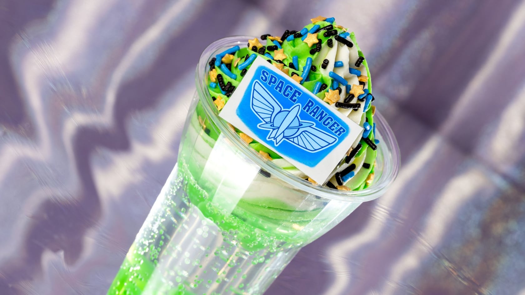 A Space Ranger Float with soft serve ice cream, topped with sprinkles and a piece of candy that has the words ‘Space Ranger’ on it