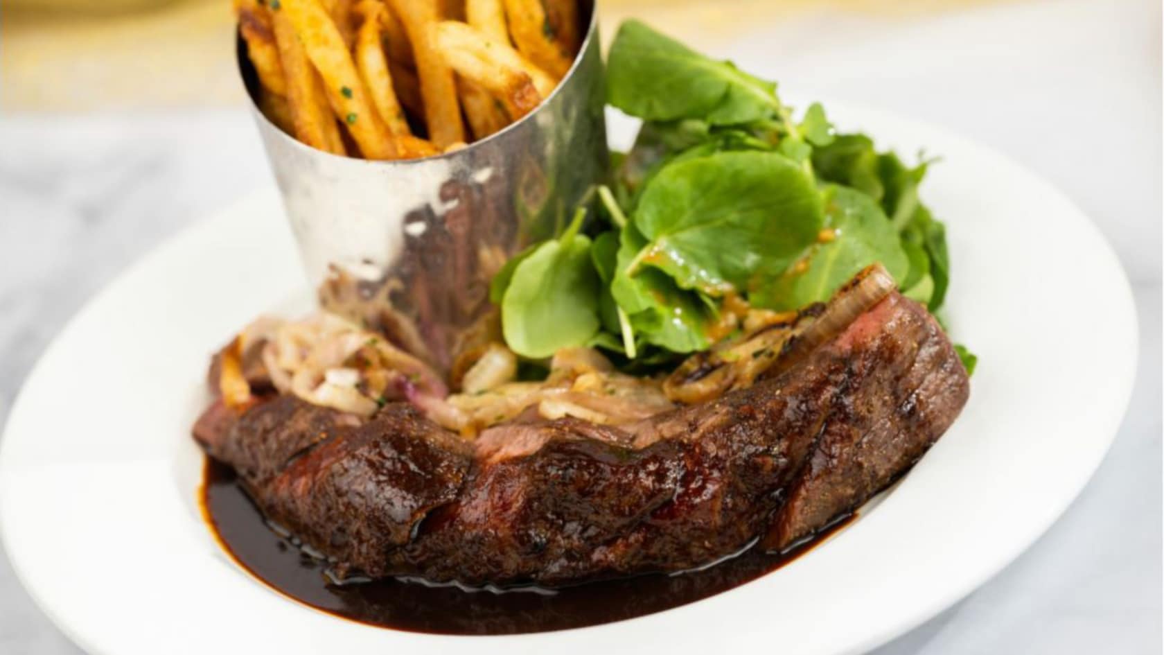 A plate of Steak Frites and a small salad from Be Our Guest
