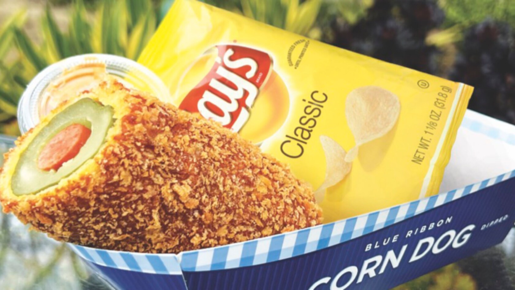 A Pickle Dog alongside a bag of potato chips with a small container of peanut butter