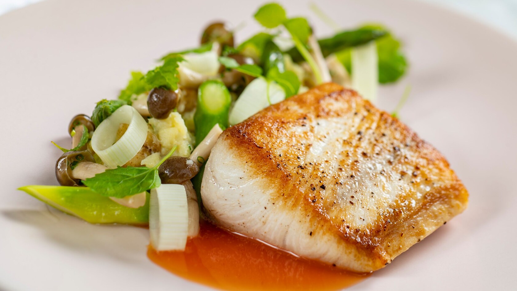 A piece of white fish served with a salad of asparagus, mushrooms and potatoes