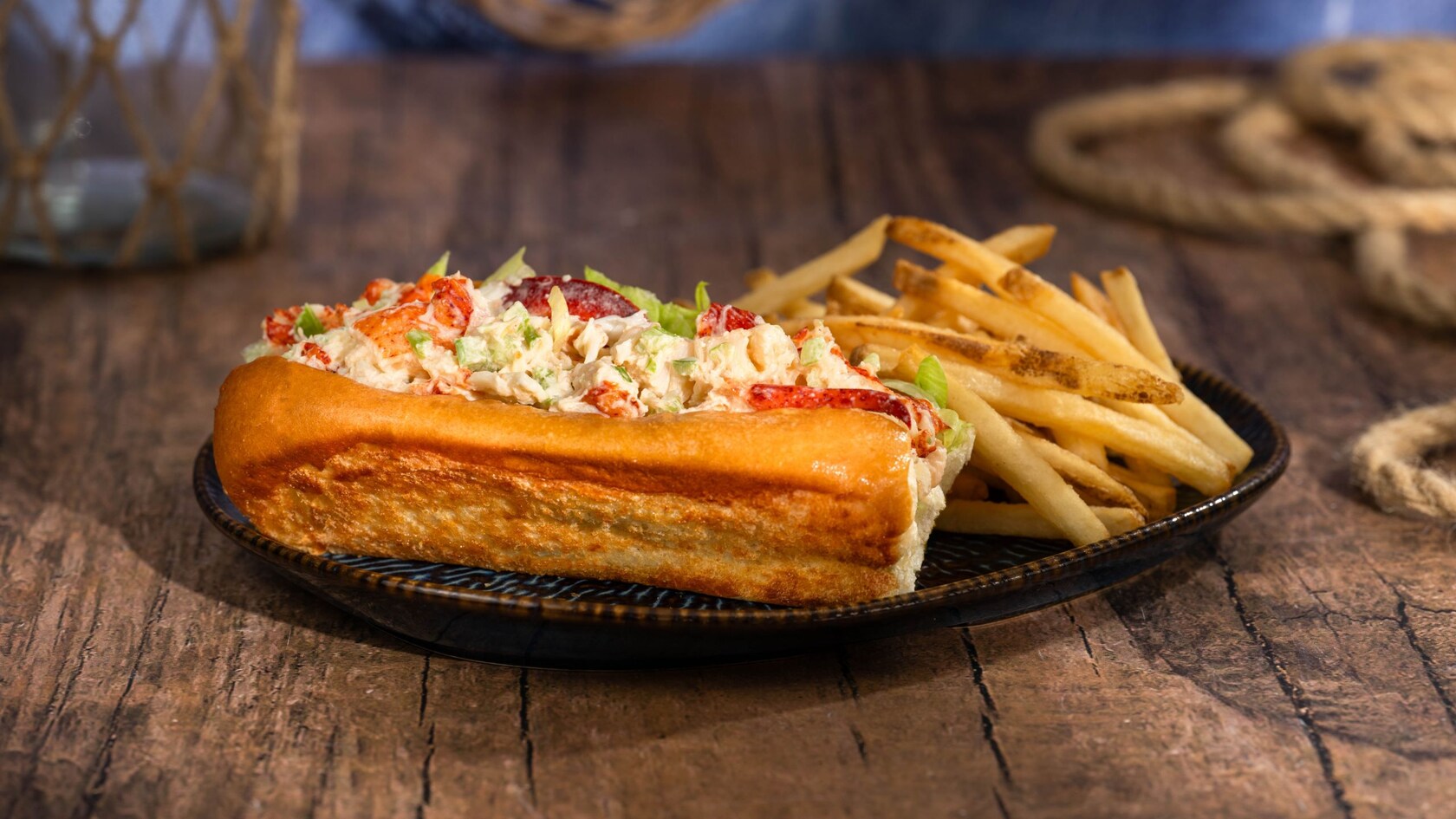 A lobster roll plated next to a pile of French fries