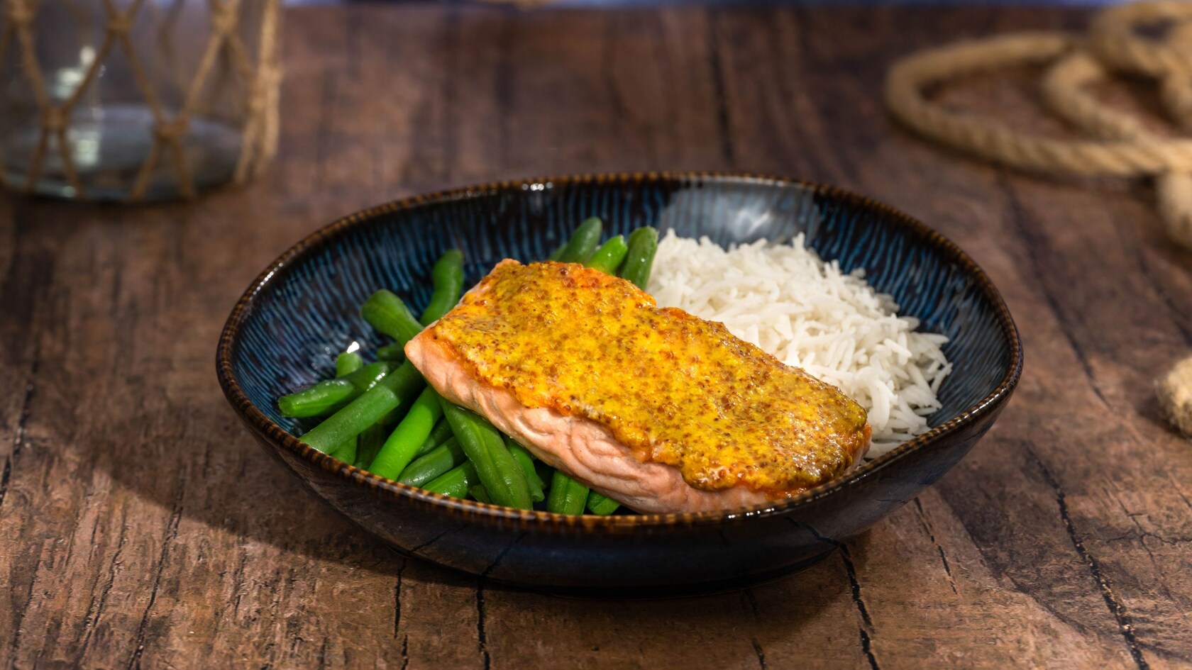 Maple mustard glazed salmon on top of rice and green beans in a bowl