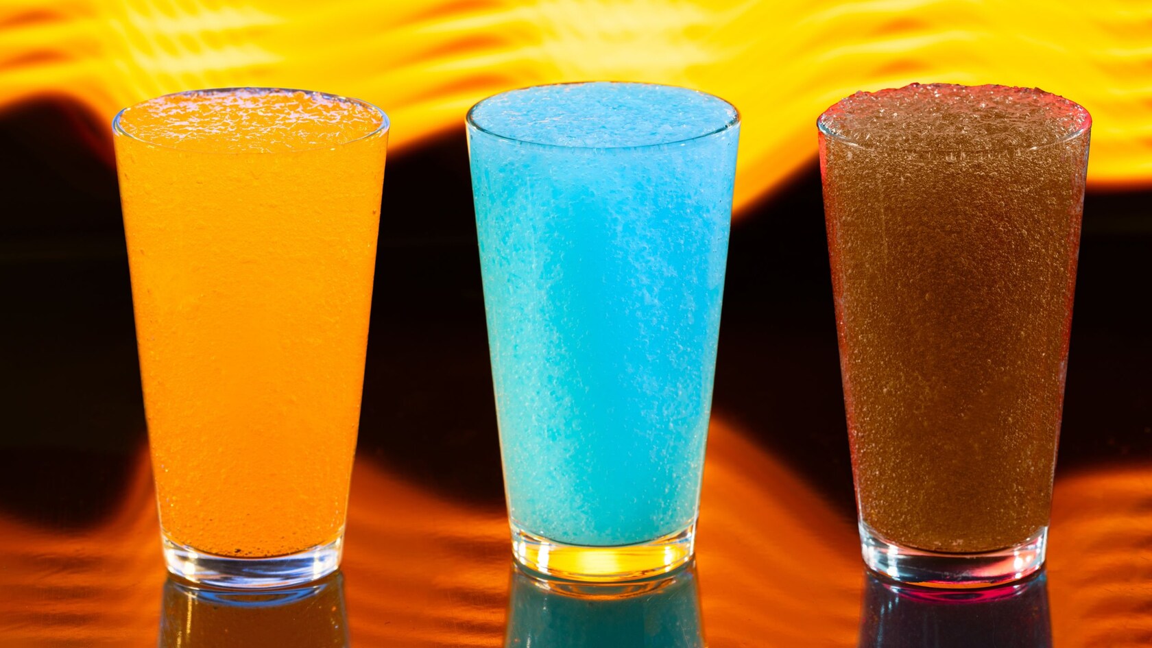 Tres vasos con granizado congelado de color naranja, azul y marrón de Astrofizz