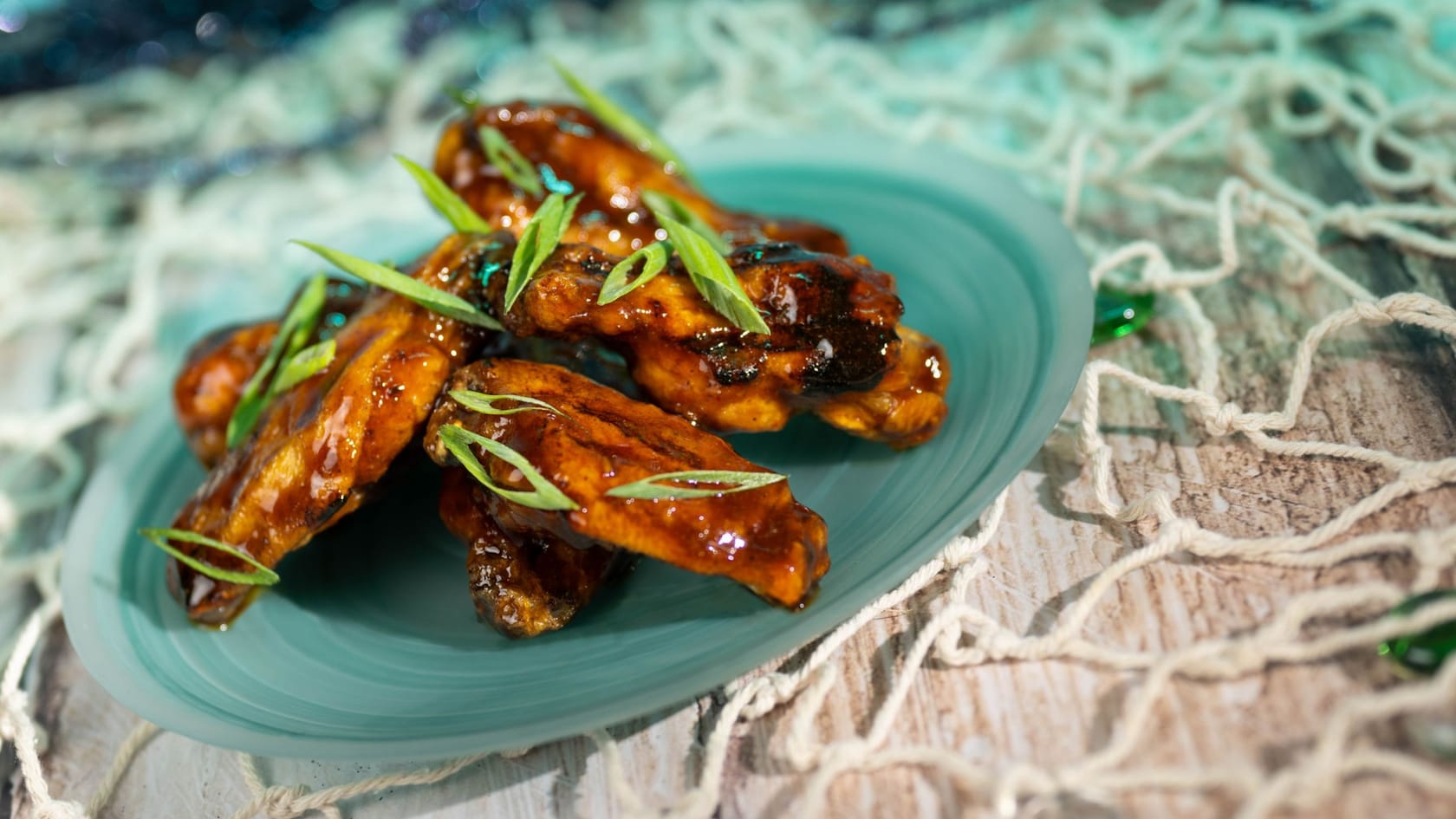 Un plato de Alitas de Pollo Asado cubiertas con cebolletas picadas disponible en Coral Reef Restaurant en Epcot