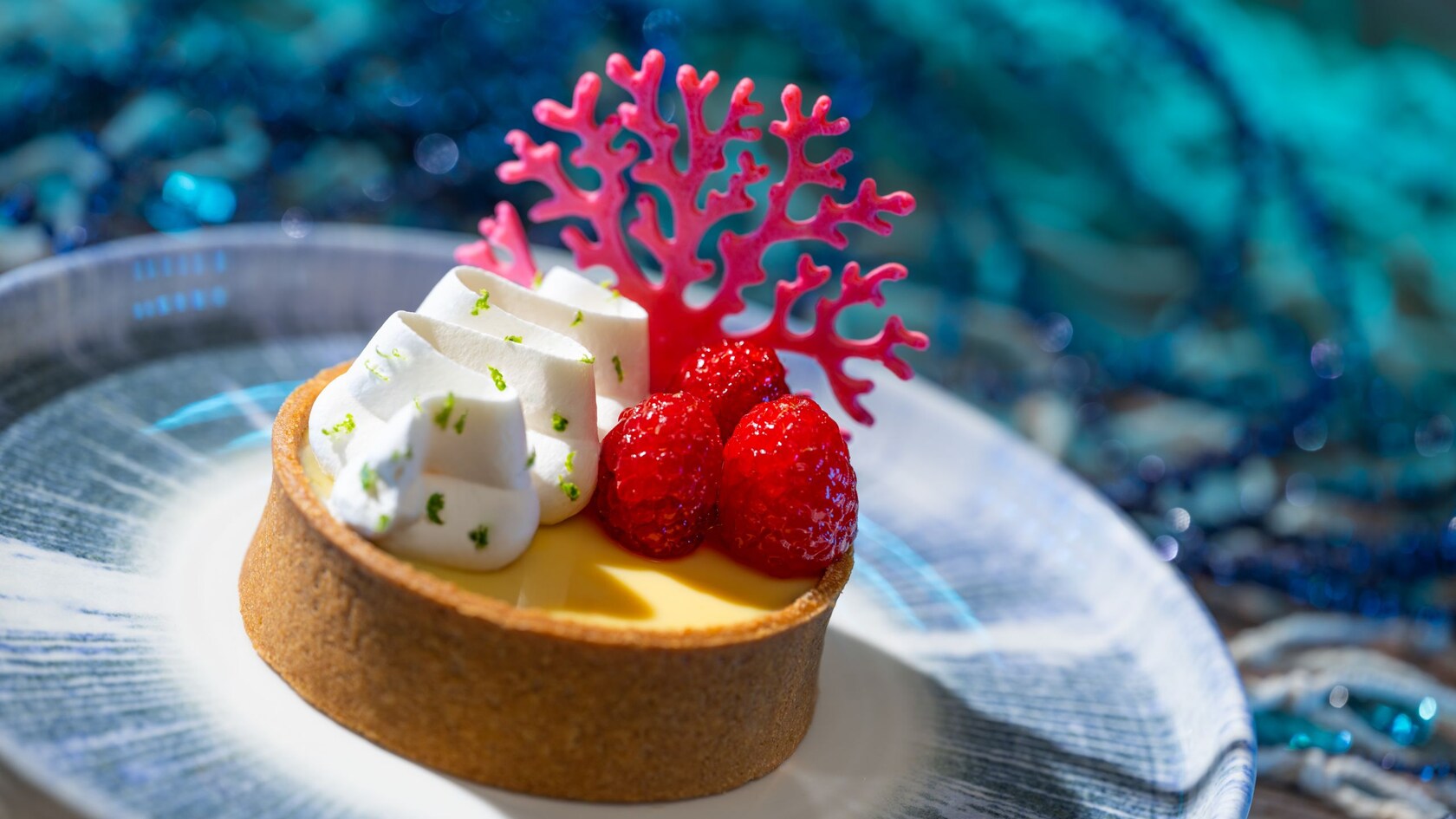 A plate with a Key West Sunset dessert topped with whipped cream and raspberries available at Coral Reef Restaurant at Epcot